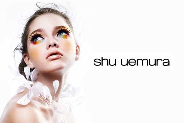 Model with colorful makeup and feather accessories, next to the "shu uemura" logo.