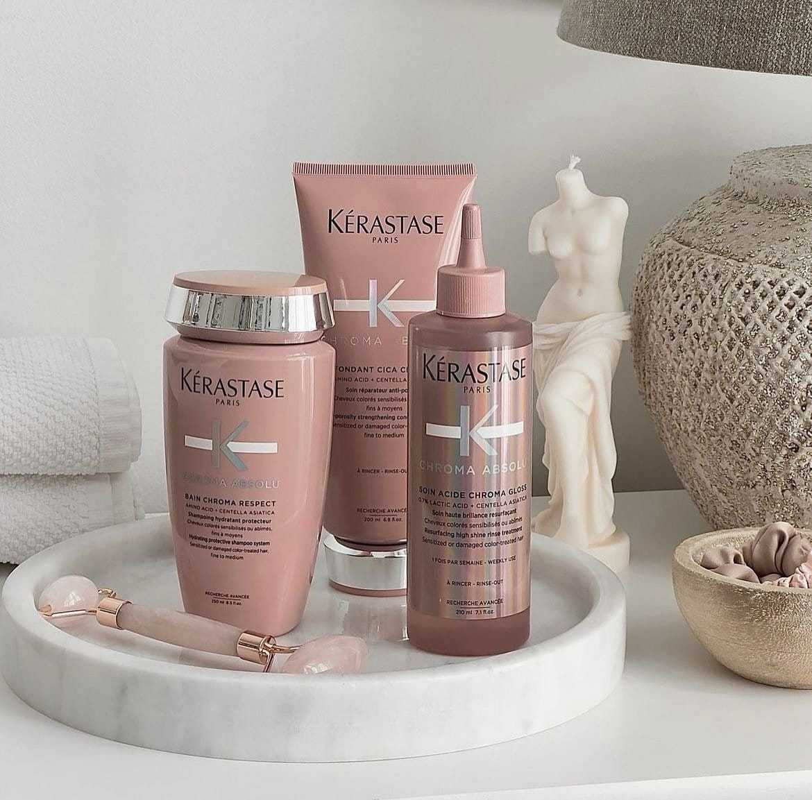 Kerastase hair products on a marble tray with decorative items nearby.